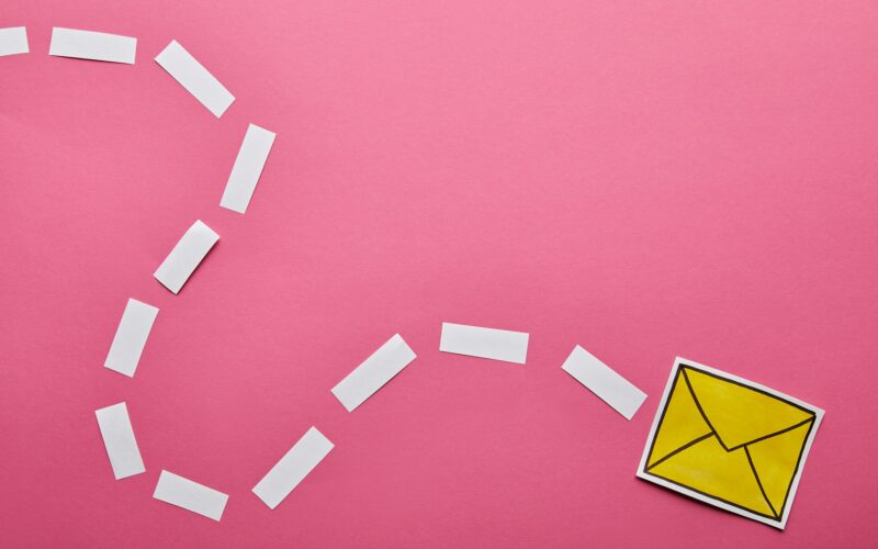 top view of yellow sending delivering email sign on pink background